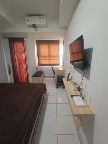 a room with a bed and a desk and a television at Paps property in Bandung