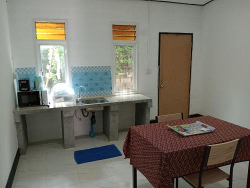 a kitchen with a table and a sink and a table with at Lanta Beautiful beach house in Ko Lanta