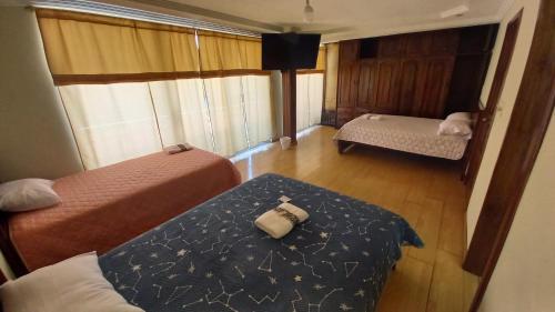 um pequeno quarto com duas camas e uma janela em MANDALA HOSTAL CUENCA em Cuenca