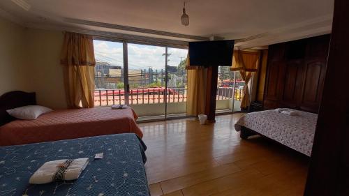 MANDALA HOSTAL CUENCA في كوينكا: غرفة فندقية بسريرين ونافذة كبيرة