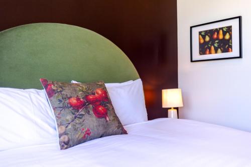 a bed with a pillow with a green head board at The White Swan Hotel in Greytown