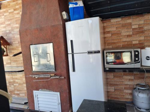 a refrigerator next to a brick wall with a microwave at Pousada Refugio Paradisíaco 2 in Piçarras