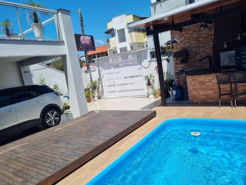 a car parked next to a house with a swimming pool at Pousada Refugio Paradisíaco 2 in Piçarras