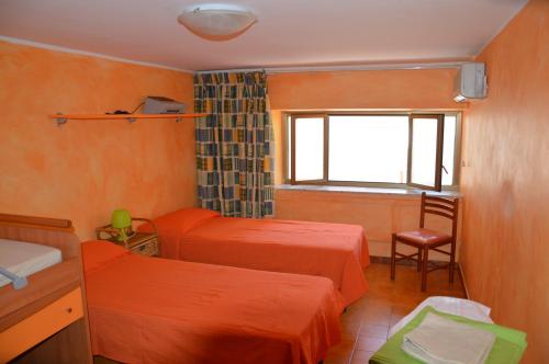 a bedroom with two beds and a window and a chair at Giocasa in Gioiosa Marea