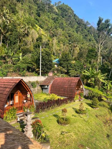 a group of huts in a field with a mountain at Villa Lumbung Ayu Sari & Spa in Karangasem