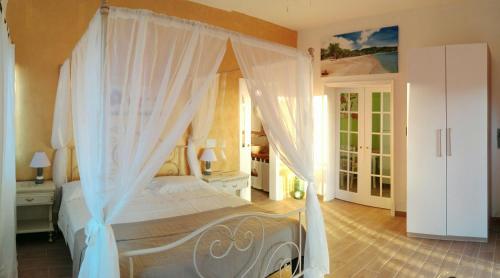 a bedroom with a canopy bed with white curtains at Donkey on the Beach in Cobbs Cross