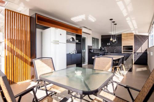 eine Küche und ein Esszimmer mit einem Glastisch und Stühlen in der Unterkunft Linda e luxuosa cobertura na praia do Forte, Cobertura Sol De Verão in Cabo Frio