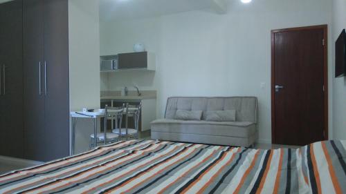 a bedroom with a bed and a couch and a kitchen at Loft Florianópolis no Campeche in Florianópolis