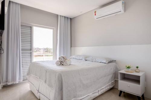 ein weißes Schlafzimmer mit einem weißen Bett und einem Fenster in der Unterkunft Linda e luxuosa cobertura na praia do Forte, Cobertura Sol De Verão in Cabo Frio