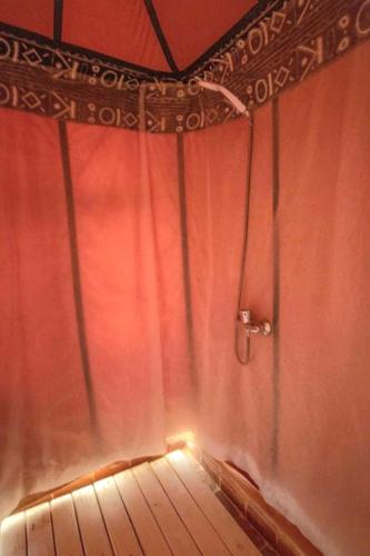 a room with a shower with a red curtain at loubna merzouga luxury camp in Merzouga