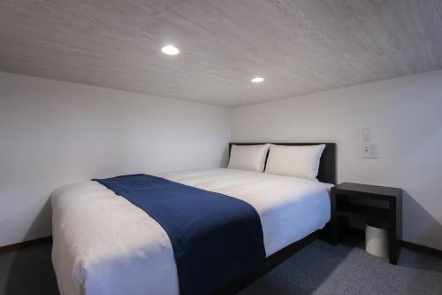 a bedroom with a large white bed in a room at Ivory Ekihigashi in Fukuoka