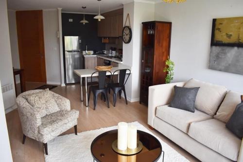 a living room with a white couch and a table at Acogedor Departamento en Zona Residencial in Puerto Varas