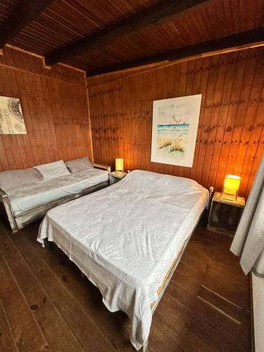 a bedroom with two beds in a wooden wall at Serendipia in Maldonado