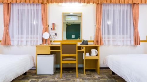 a desk in a room with two beds and a mirror at Toyoko Inn Hirosaki Ekimae in Hirosaki