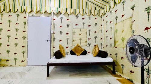 a room with a bed and a fan and a wall at DESERT OVERNIGHT LUXURY CAMP & ReSORT in Jaisalmer