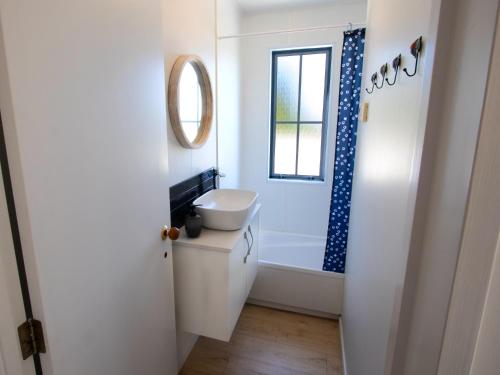 a bathroom with a toilet and a tub and a window at The Lighthouse - Ligar Bay Holiday Home in Tarakohe