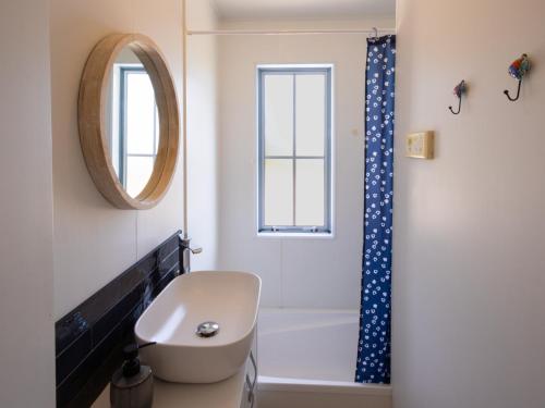 a bathroom with a toilet and a sink and a mirror at The Lighthouse - Ligar Bay Holiday Home in Tarakohe