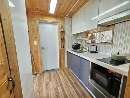 a kitchen with a white door and wooden floors at Jeju Nova Pension in Jeju