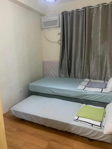 two beds in a small room with a window at Seawind Condominium Near Airport in Davao City