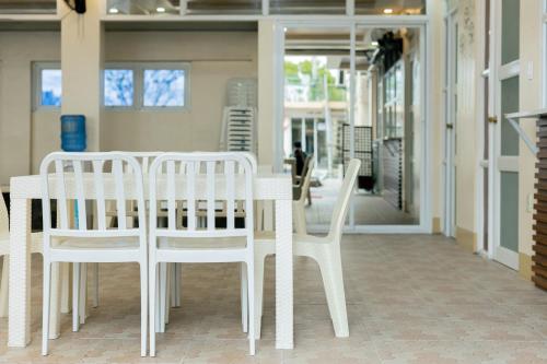 2 weiße Stühle und ein Tisch in einem Gebäude in der Unterkunft Villa Baldeo Resort in Campo