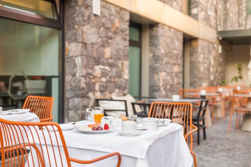 a table with plates of food on it in a restaurant at Castanheiro Boutique Hotel in Funchal