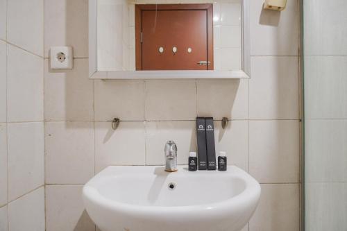 a white sink in a bathroom with a mirror at High Floor and Comfort Living 2BR Apartment at Thamrin Residence By Travelio in Jakarta