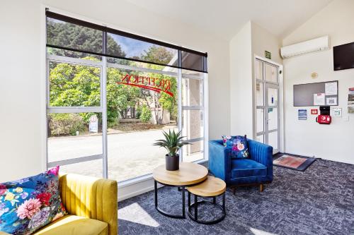 a living room with two chairs and a table and a window at Balmoral Lodge Motel in Invercargill