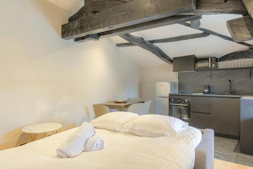 a white bed in a room with a kitchen at Appartement paisible et confortable, Salvagny in La Tour-de-Salvagny