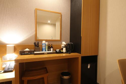 a room with a desk with a mirror and a phone at Hotel Prima Busan in Busan