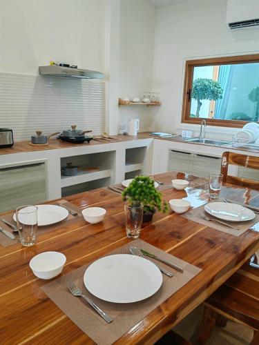 a wooden table with white plates on it in a kitchen at Turtle Tales-Tahnu,Thaimueang beach,Phang-Nga in Thai Muang