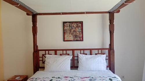 a bed with two pillows in a bedroom at Rumah Paros & Gallery in Sukawati