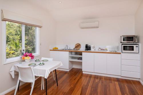 a kitchen with white cabinets and a white table and chairs at The Whale Lookout, Eagle Bay in Dunsborough