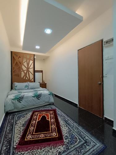 a bedroom with a bed with a rug on the floor at Al Funduq Motel in Jitra