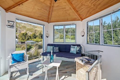 a living room with a blue couch and chairs at The Lighthouse - Ligar Bay Holiday Home in Tarakohe