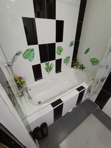 a bathroom with a bath tub with black and white tiles at Al Funduq Motel in Jitra