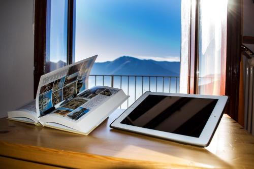 a tablet and a book on a table with a window at Ristorante Bellavista con Locanda in Veleso