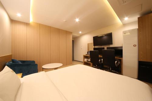 a room with a bed and chairs and a tv at Hotel Prima Busan in Busan