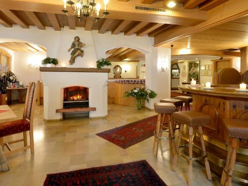 a living room with a fireplace and a bar with stools at Alpenhotel Kramerwirt in Mayrhofen