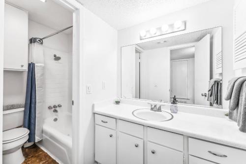 a white bathroom with a sink and a mirror at Heart of SoCo 2BR and 1BR King Suites with Free Parking, Pool, and Laundry Center in Austin