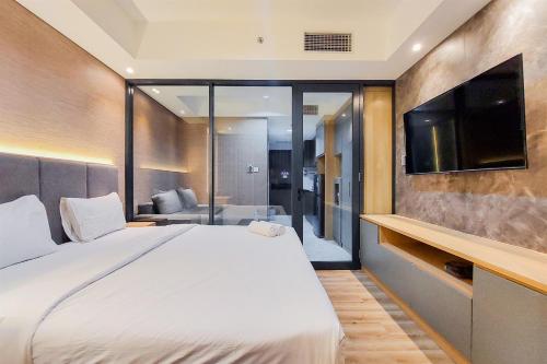 a bedroom with a large bed and a flat screen tv at Fancy and Comfortable 1BR The Smith Alam Sutera Apartment By Travelio in Tangerang