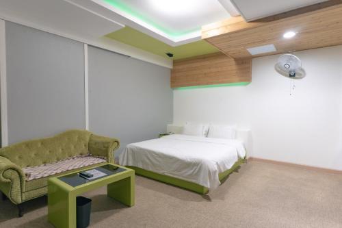 a bedroom with a bed and a couch and a chair at The Bay Hotel Haeundae in Busan