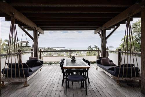 a porch with swings and a table and chairs at THE BEACH HAVENS in Emerald Beach