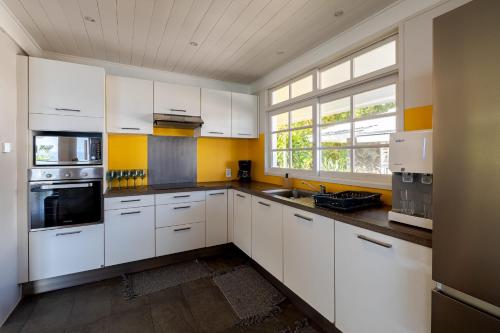 a kitchen with white cabinets and a large window at Domaine To'a Hotu in Tohautu
