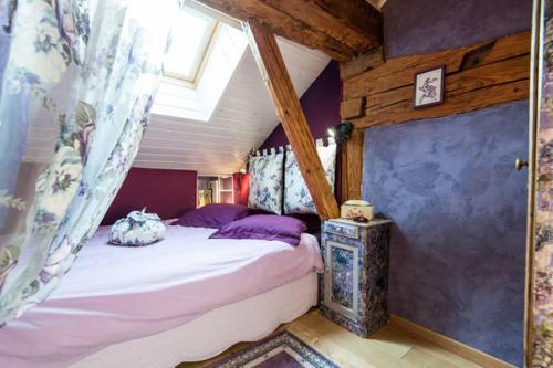 1 dormitorio con cama con dosel y almohadas moradas en Gîte Du Margouillat, en Saint-André-de-Boëge