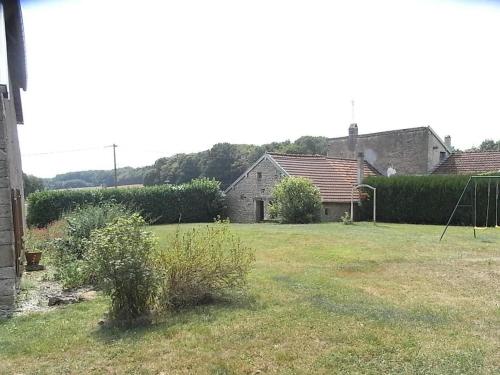 a yard with a house in the background at Chambres Confortables avec Petit Déjeuner Inclus et Salon de Jardin - FR-1-583-284 in Melin