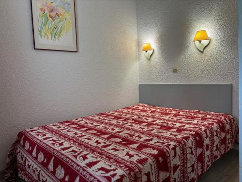 - une chambre dotée d'un lit avec une couverture rouge et blanche dans l'établissement Charmant T2 Terrasse Parking - Proche Pistes - FR-1-329-98, à La Plagne Tarentaise