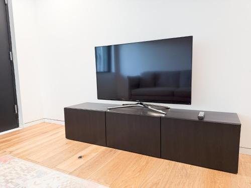 a black entertainment center with a large television on a wall at Exquisite and Modern Stay in Brooklyn at Rem-Casa in Brooklyn