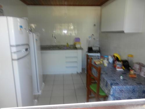 a kitchen with a table and a white refrigerator at Casa 4 quartos em Guarajuba, excelente localização! 200m da praia! in Camacari