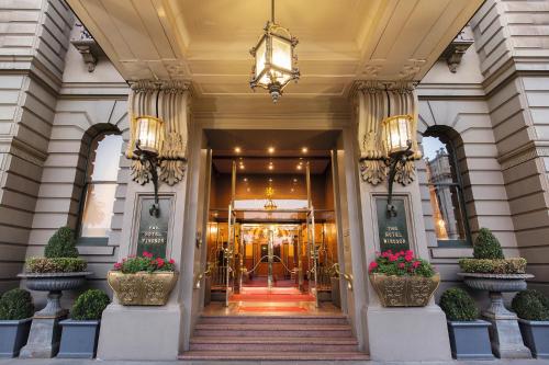 a lobby of a hotel with two potted plants at The Hotel Windsor in Melbourne
