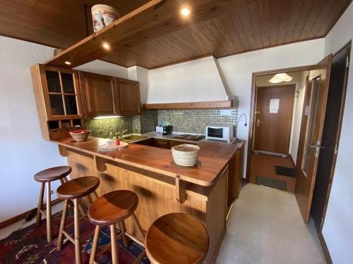 - une cuisine avec des comptoirs en bois et des tabourets dans l'établissement Studio cosy pour 2 personnes proche des pistes, vue sur les Aravis - FR-1-733-157, à Crest-Voland